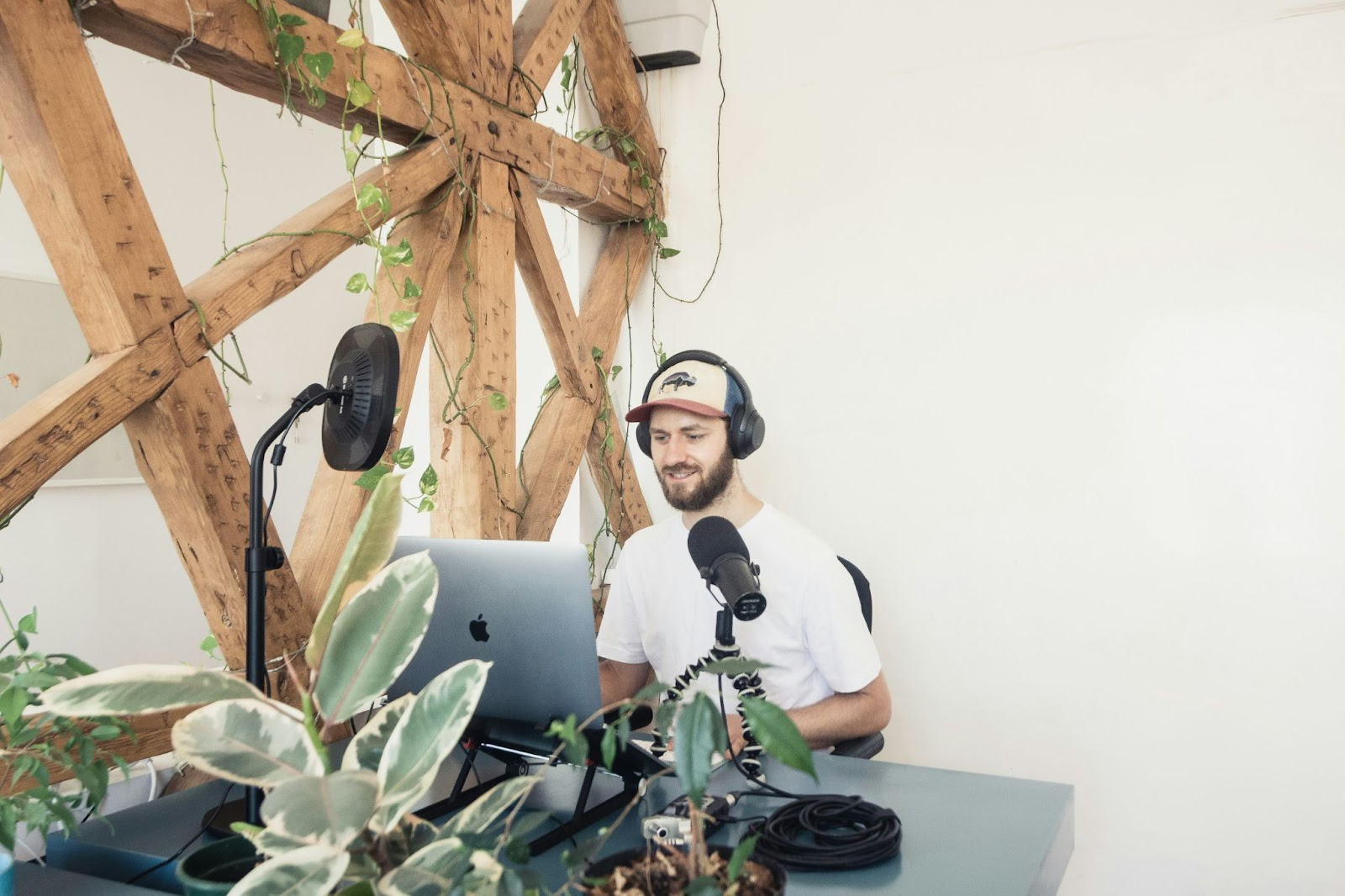 Podcaster wearing headphones recording an episode with a microphone and laptop